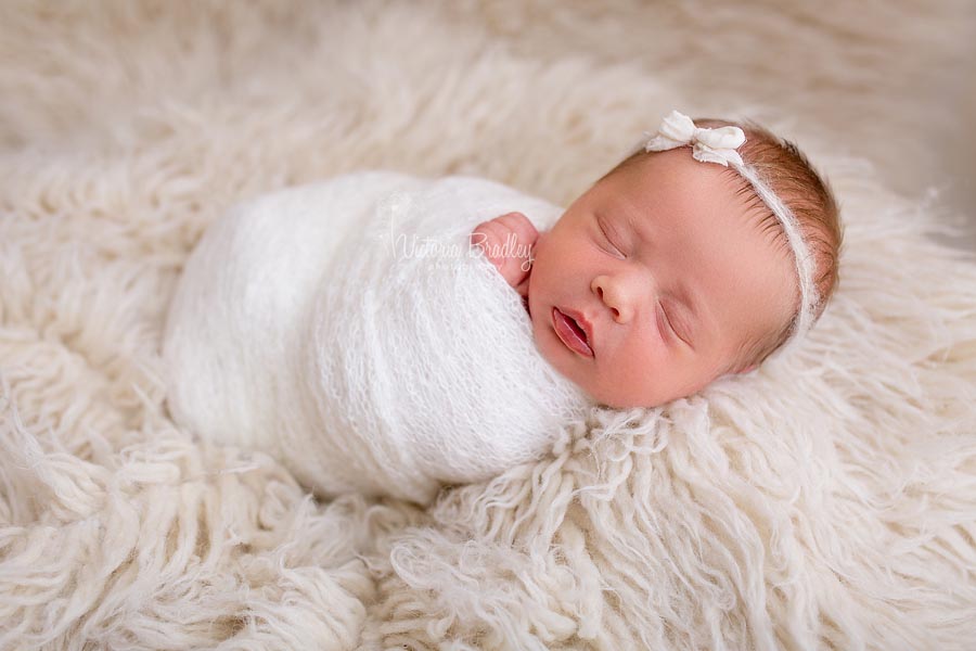 Newborn wrapped baby with bow, cream colours