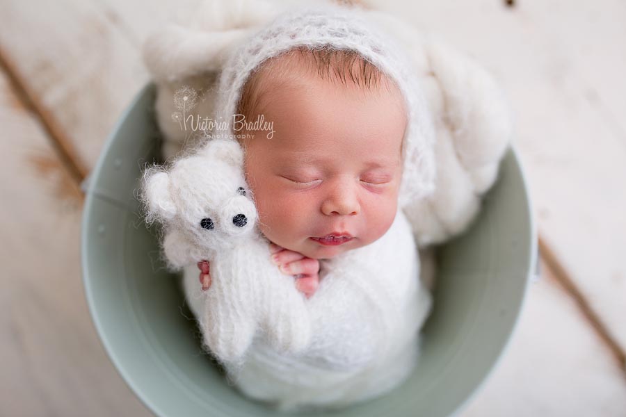 newborn wrapped baby holding little teddy, cream colours