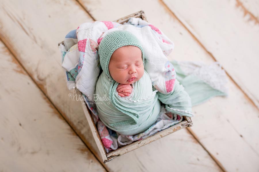 wrapped newborn image with vintage quilt, mint wrap & bonnet