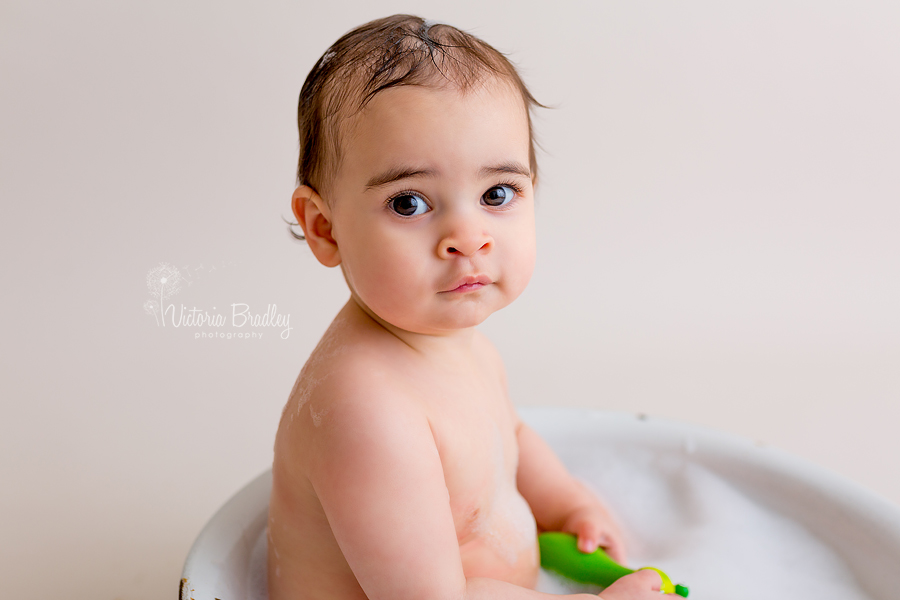 baby in white enamel bath tub with bubbles
