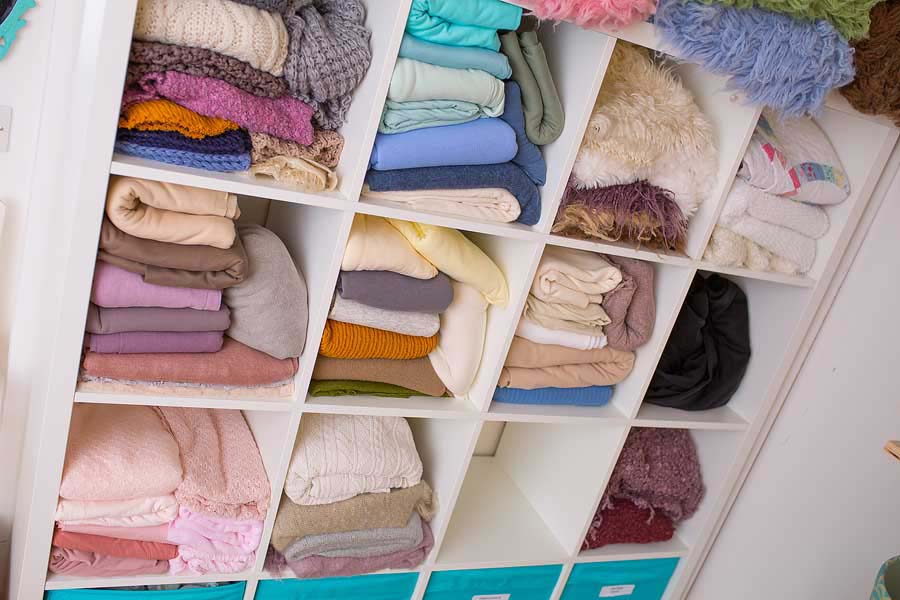 a white rack full of coloured blankets and flokati rugs