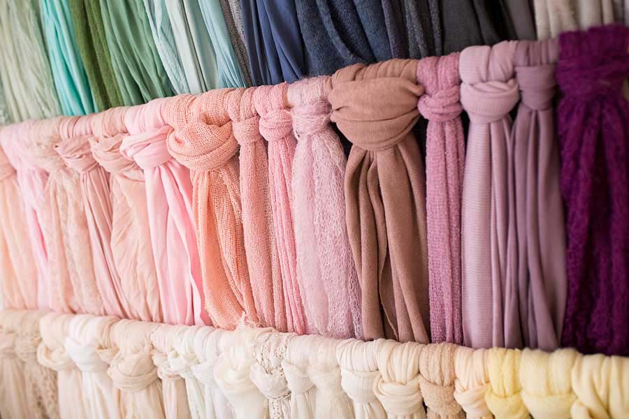 a selection of coloured fabric baby wraps of many colours