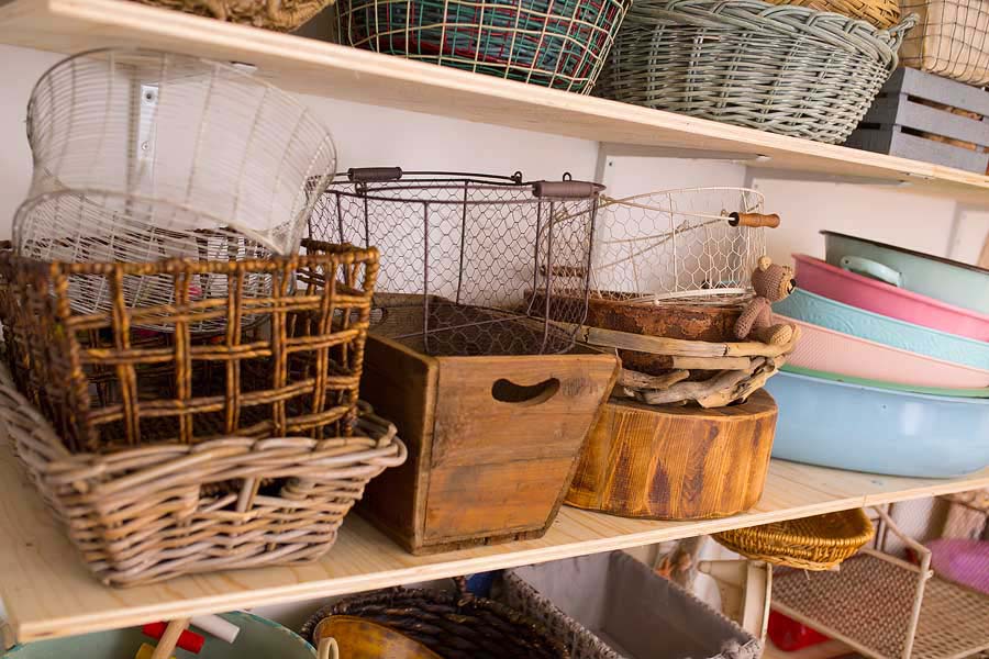 a shelf stacked with various vintage style metal baskets and wooden crates