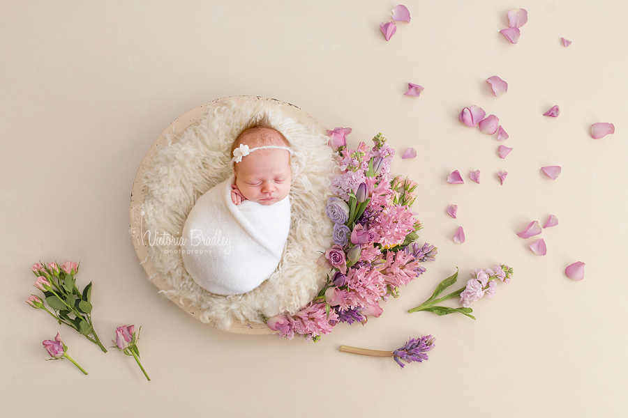 pretty floral bowl with newborn baby girl wrapped in a cream wrap