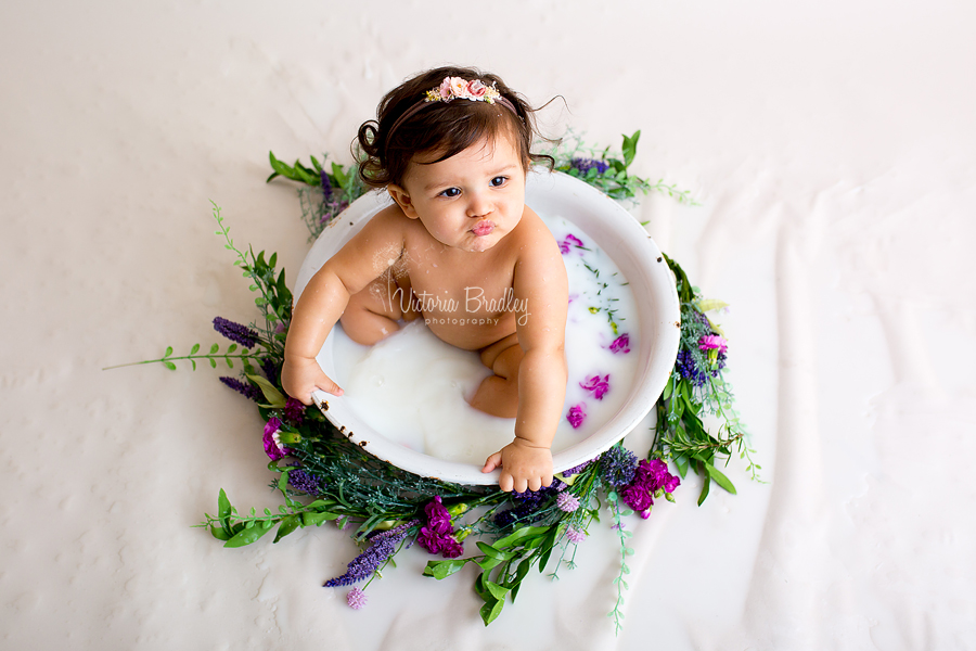 baby in milk bath with purple and green flowers