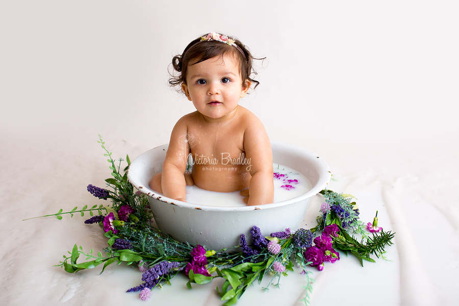 baby girl in white enamel bath tub during milk bath session