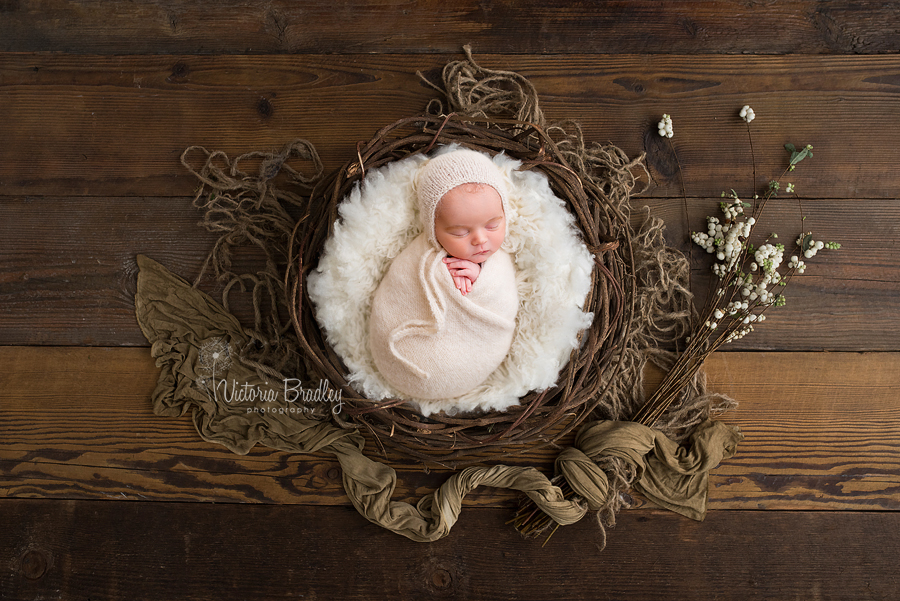 wrapped newborn in cream knitted wrap in a rustic basket