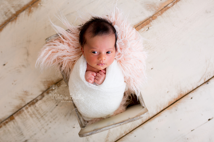 awake wrapped newborn baby girl in cream knitted wrap