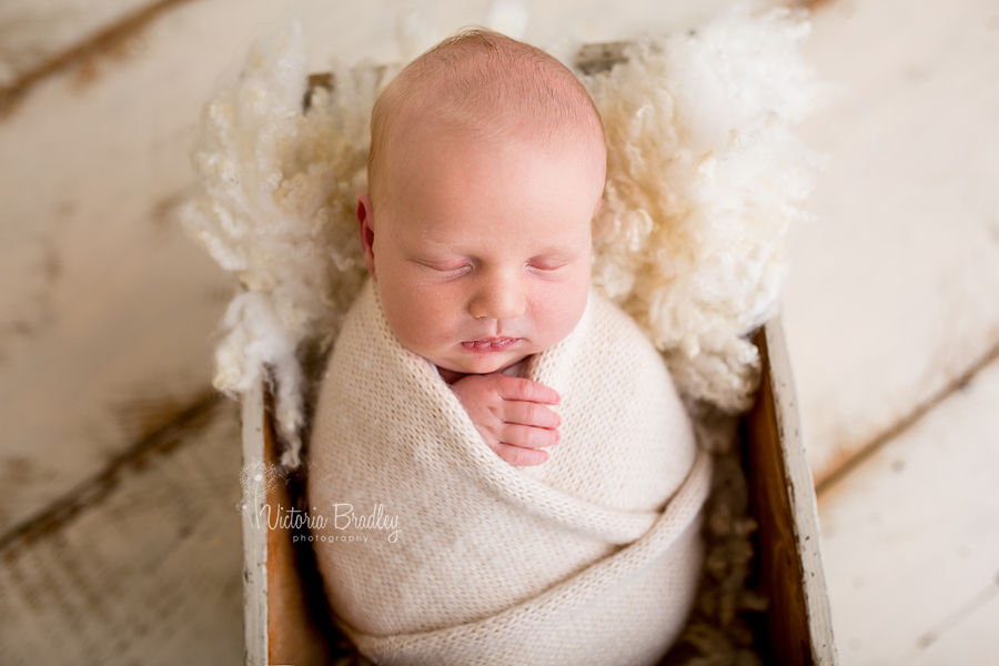 newborn baby boy in cream knitted swaddle