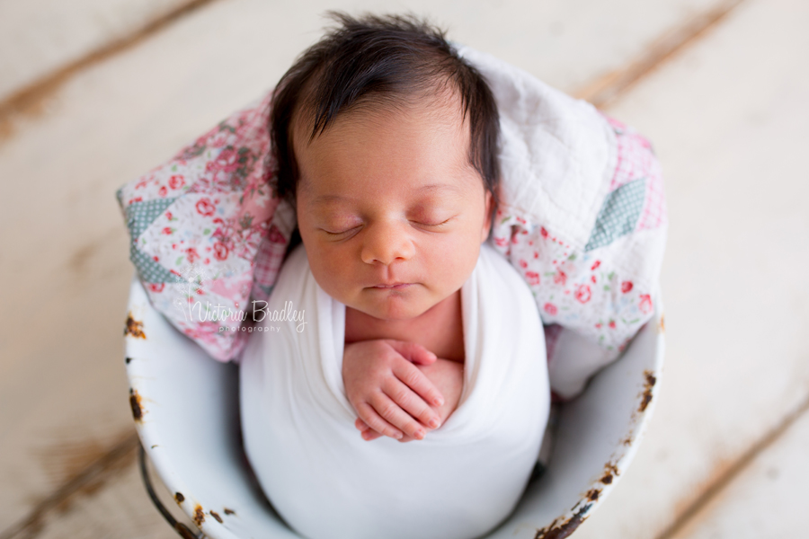 newborn baby girl in white vintage bucket with vintage quilt piece