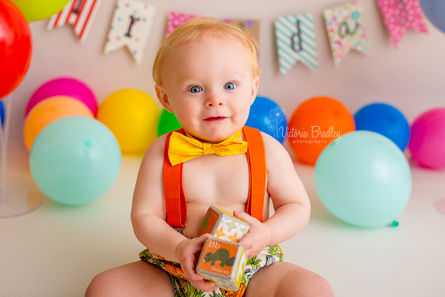 rainbow cake smash with baby boy, holding blocks