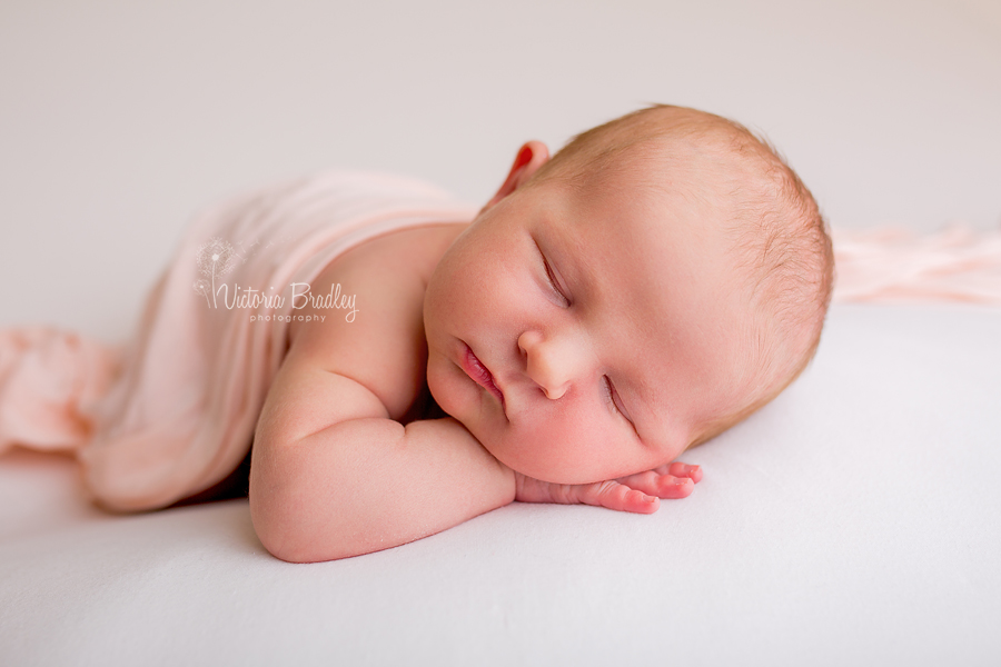 newborn baby on wrap backdrop with peach wrap