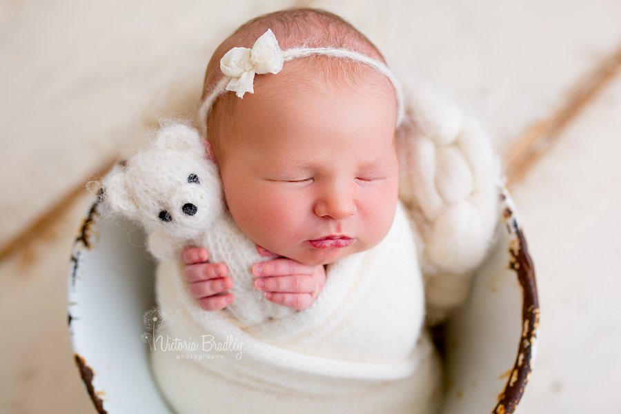 wrapped baby newborn girl with white teddy and white bow hair tie back