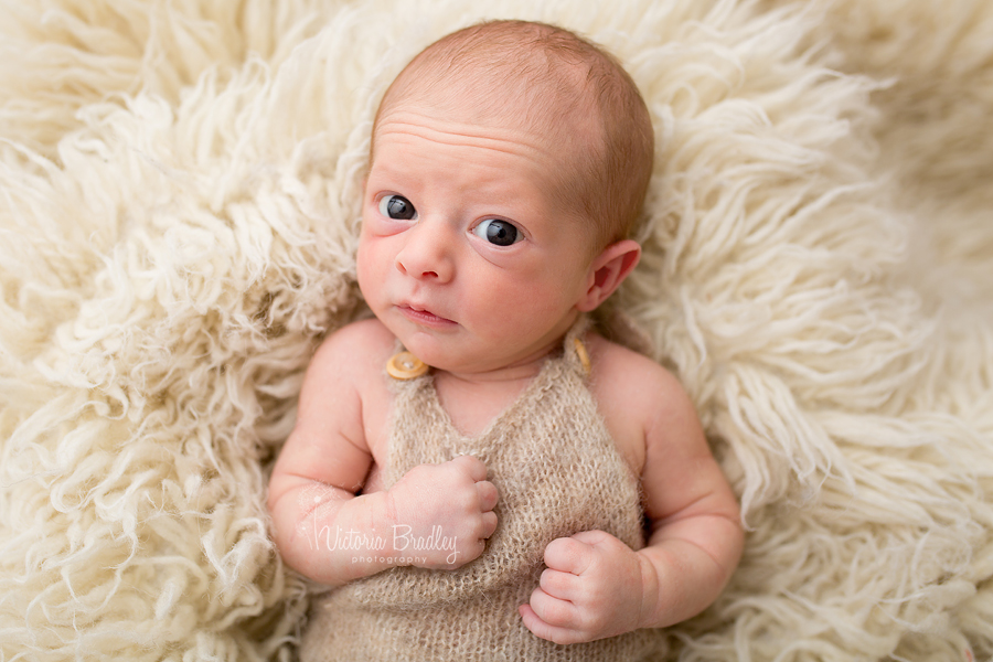 awake baby newborn boy in knitted dungarees