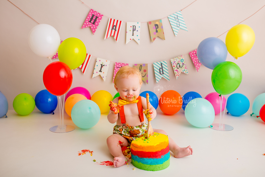 boy cake smash with rainbow cake and balloons