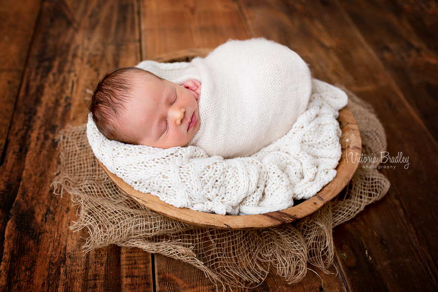 cream and dark wood with newborn with knitted cream wrap