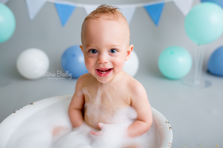 baby boy in white enamel tub smiling at camera