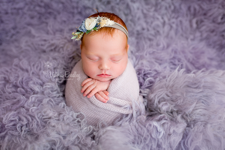 potato sack pose, newborn baby girl on lilac flokati