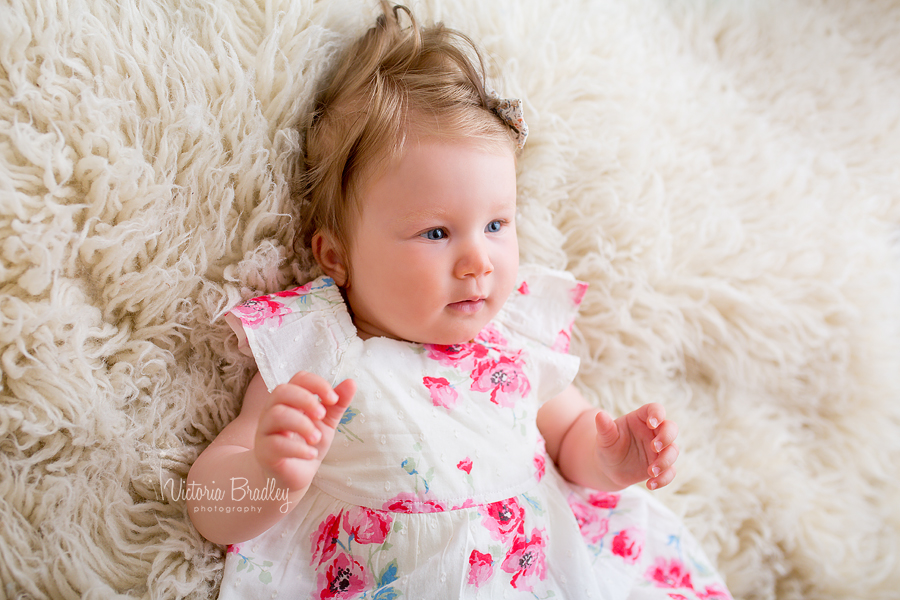 baby girl lay on cream flokati rug, sitter photographer