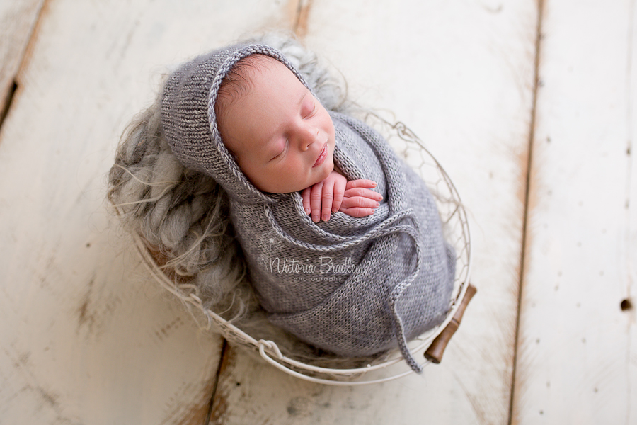 grey knitted wrap and bonnet on newborn baby boy