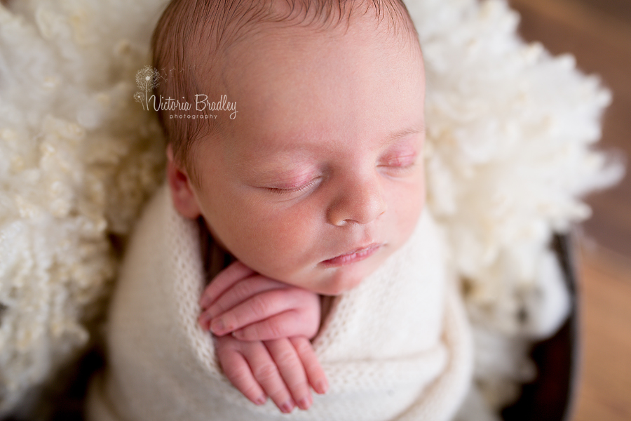 close up shot of a newborn baby wrapped in a cream wrap