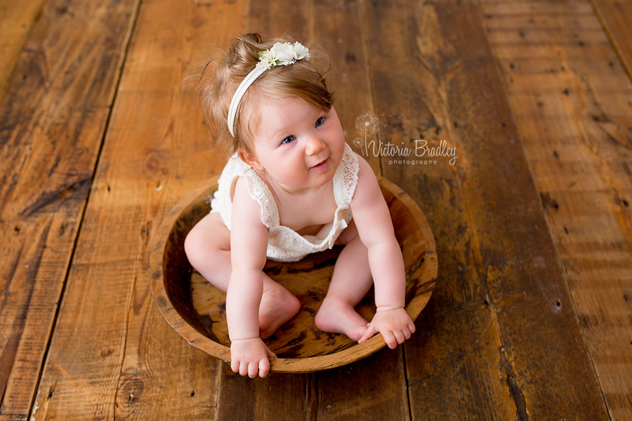 baby girl sat in wooden bowl during photography session