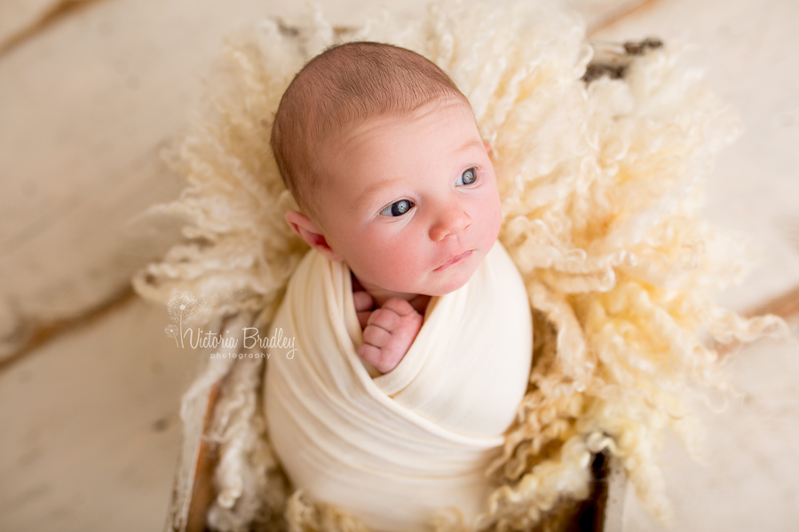 wrapped newborn girl on pale yellow fur