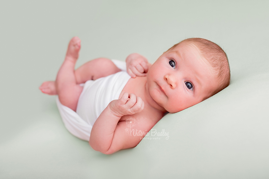 wrapped baby newborn girl on mint backdrop with white wrap
