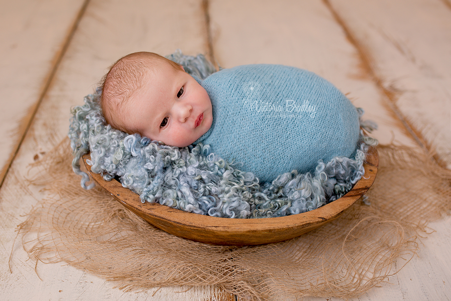 wrapped newborn in wooden bowl