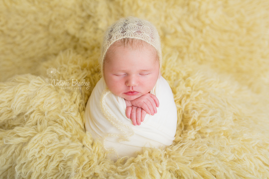 potato sack pose newborn baby girl on lemon flokati rug