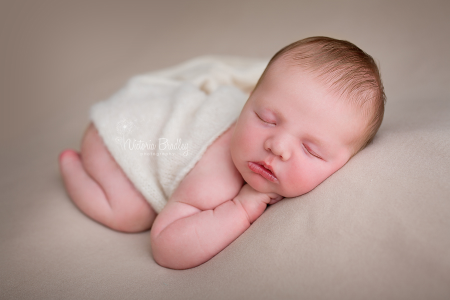 baby boy on biscuit coloured backdrop during newborn photography session