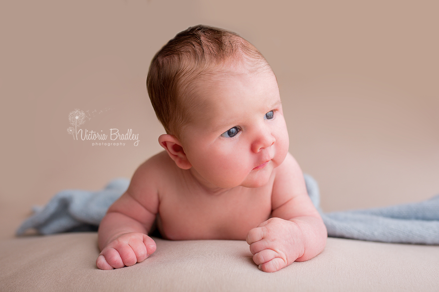 newborn looking up on cream backdrop