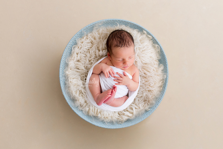 wrapped newborn boy in blue basket