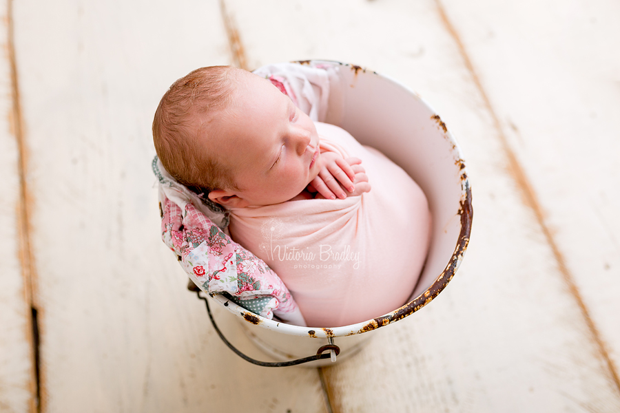 wrapped newborn baby girl in peach wrap on a in a white bucket, newborn photography studio nottinghamshire