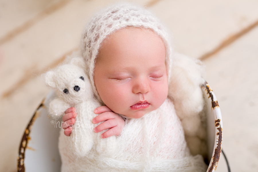 wrapped newborn baby girl in cream knitted wrap with cream bonnet and tidy teddy