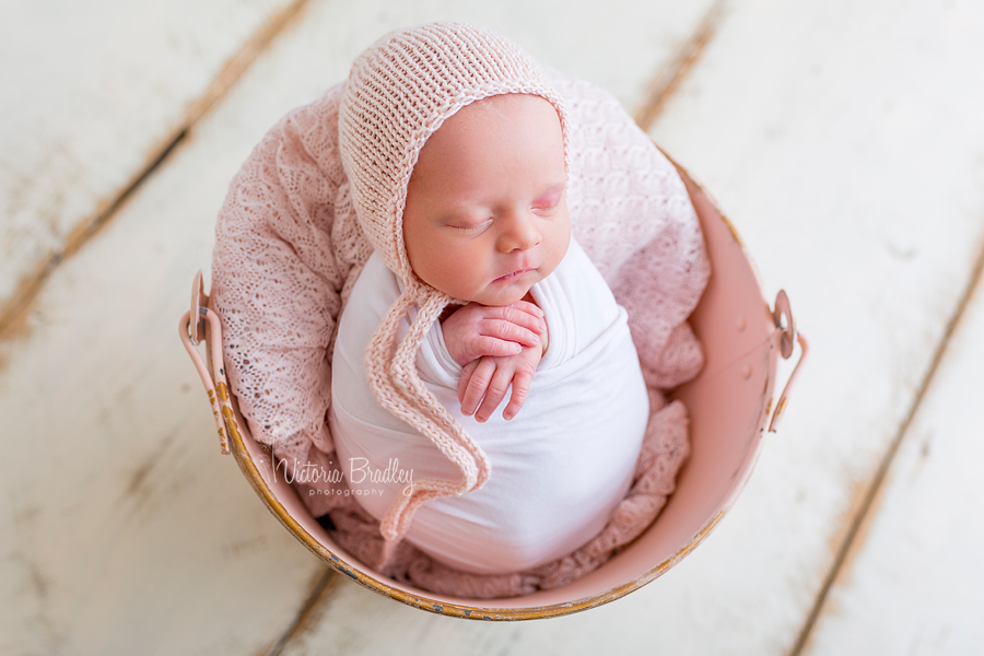 baby wrapped in pink bucket