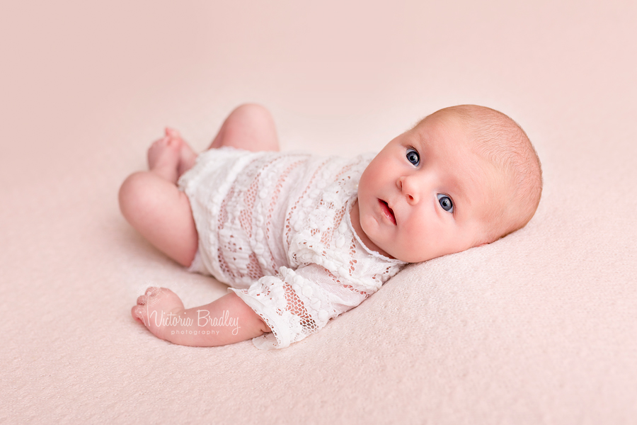 newborn baby girl photography on pale pink blanket