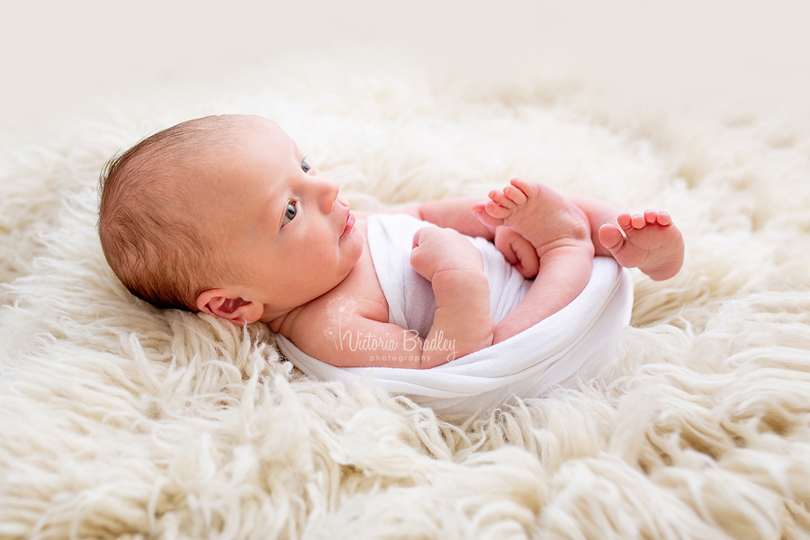 newborn photography session, baby boy on white flokati, side lit