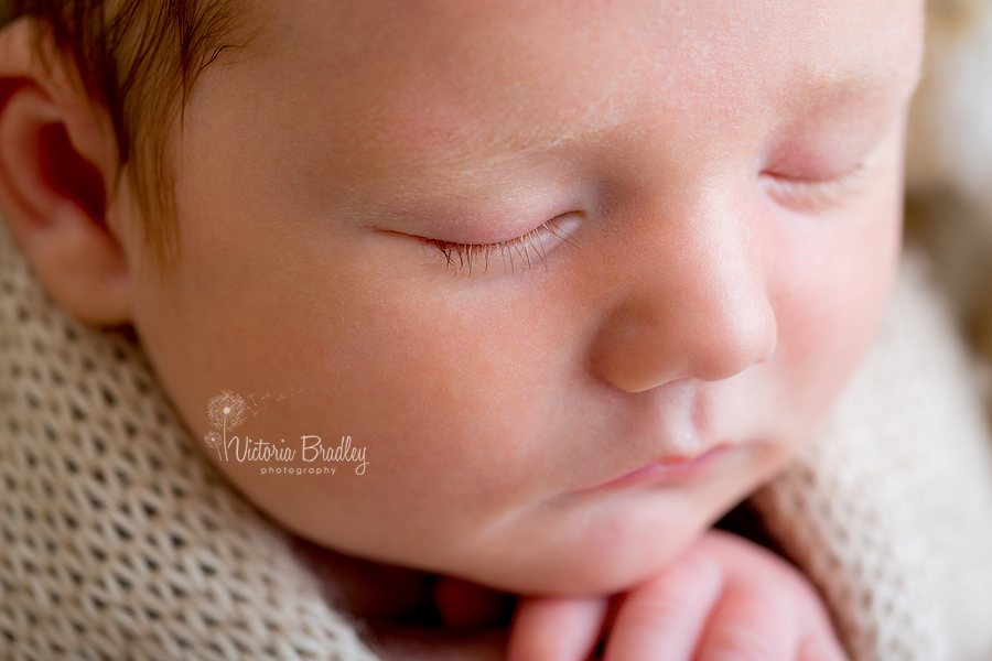 close up face shot of baby newborn in cream wrap