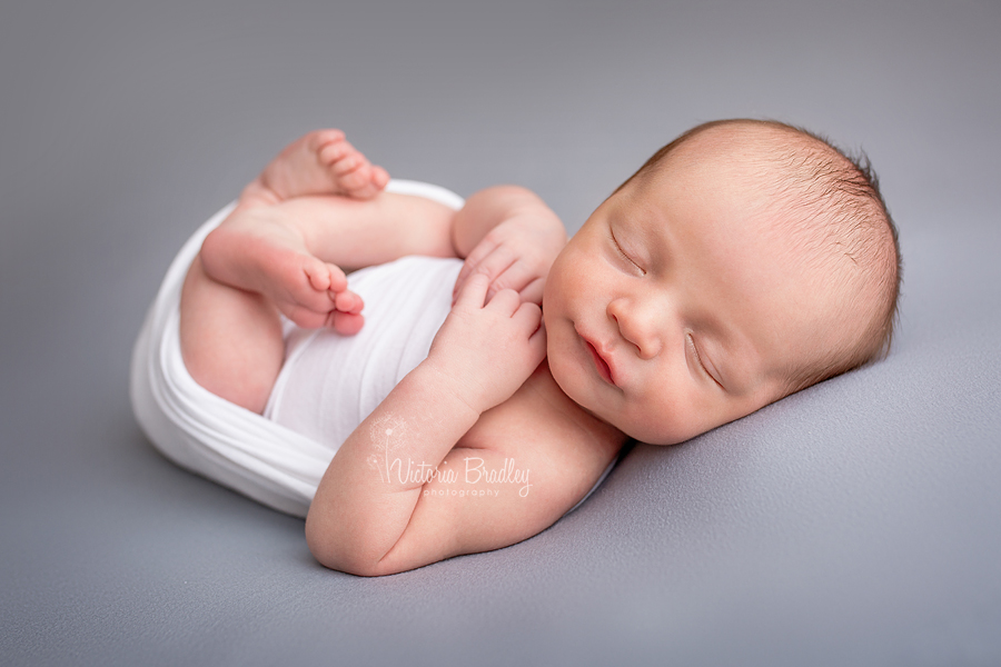 newborn photography session, baby boy in white wrap on grey backdrop