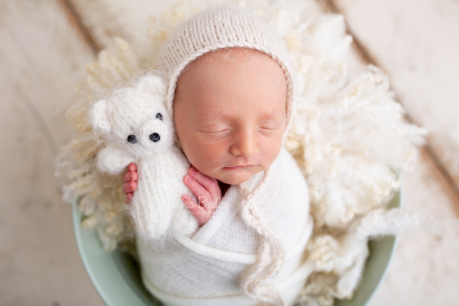 newborn holding white teddy