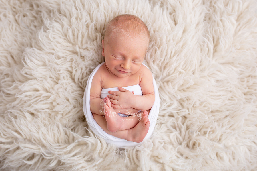 wrapped newborn on cream rug