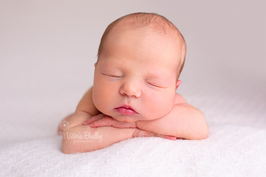 newborn photography baby girl on pink blanket, chin on hands pose