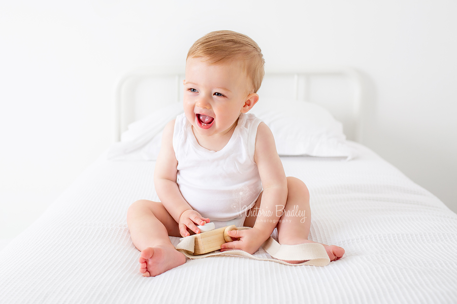 baby boy in white on white bed