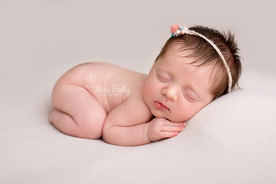 baby newborn girl photography on cream blanket with dainty flower tieback