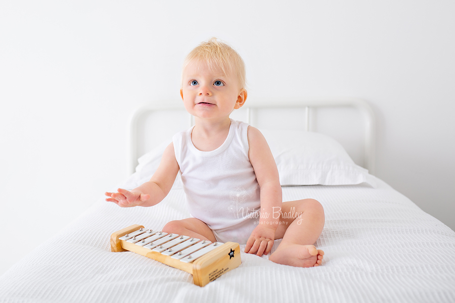 baby boy studio photography on white bed with white xylophone 