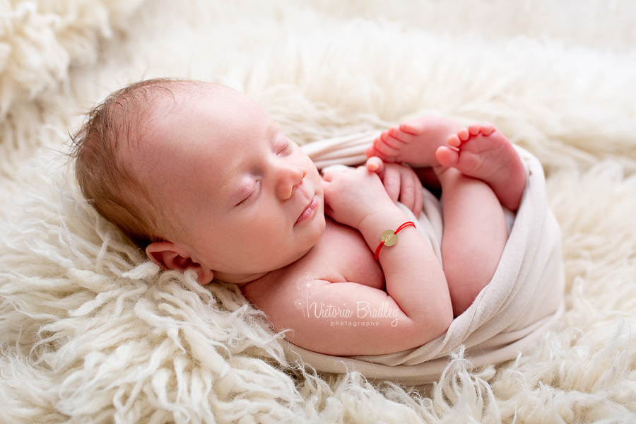 newborn baby boy on cream fluffy rug