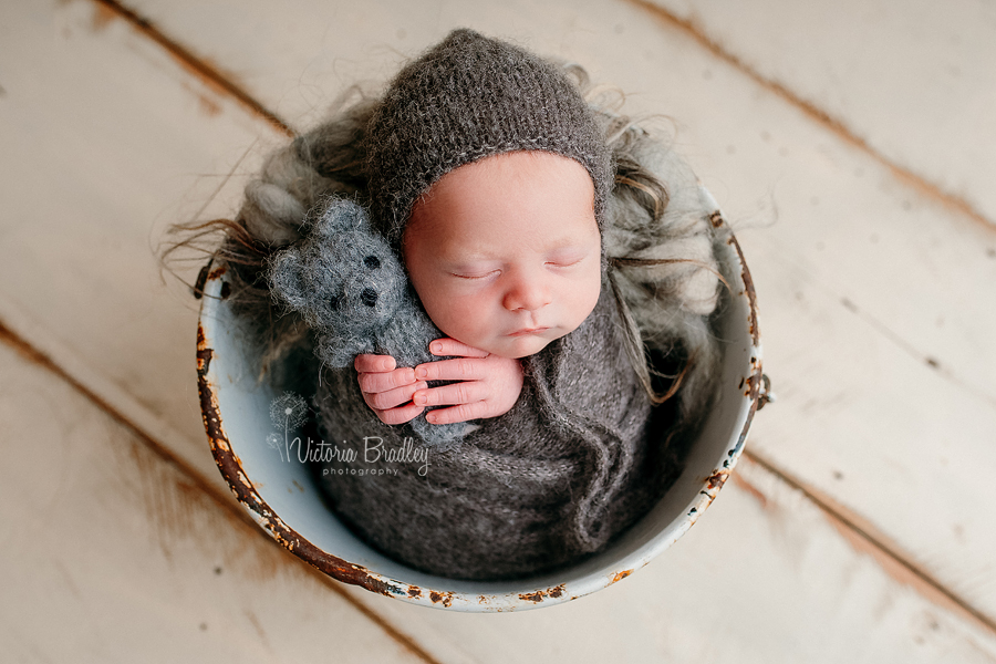 newborn baby boy photography, wrapped in a grey knitted wrap hold grey teddy