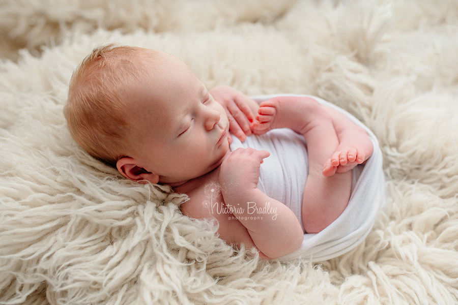 newborn baby boy photography on cream flokati rug and white wrap