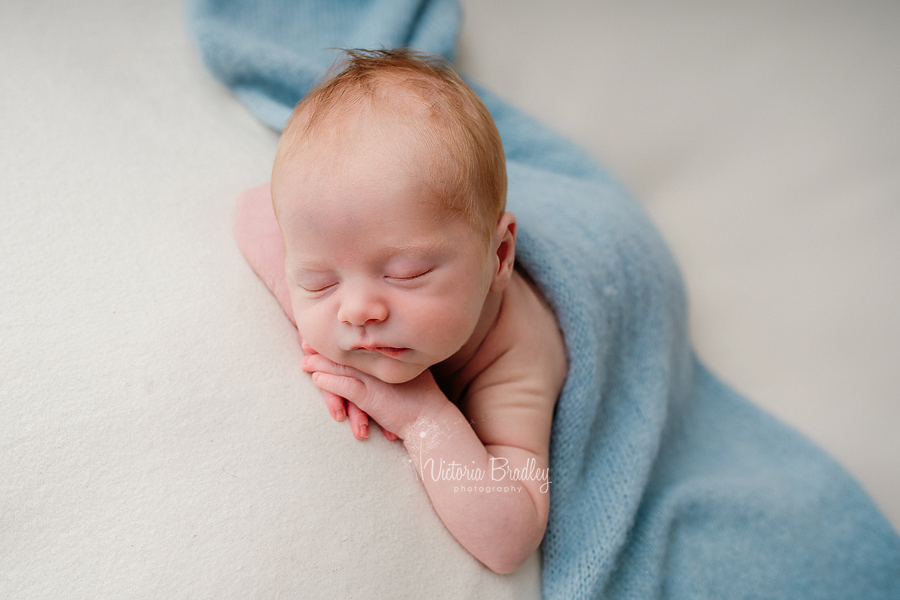 Newborn baby boy photography on tummy with blue wrap